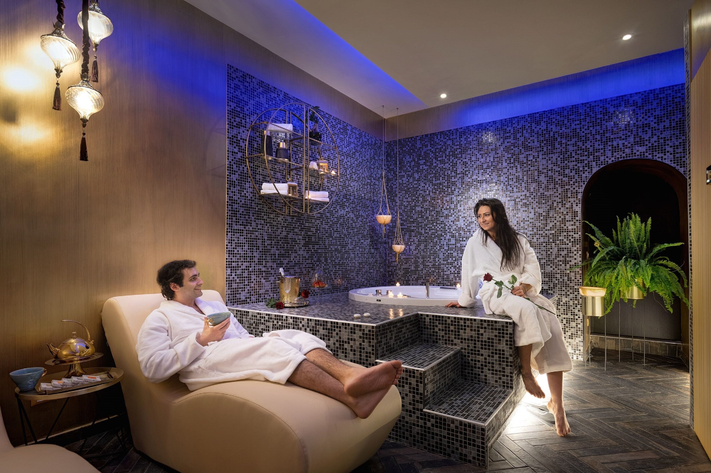 Un cuarto de spa con una silla de masaje, una bañera y un estante decorativo.