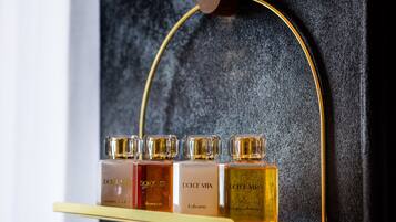 A display of Dolce Vita perfume bottles on a gold shelf against a dark textured wall.