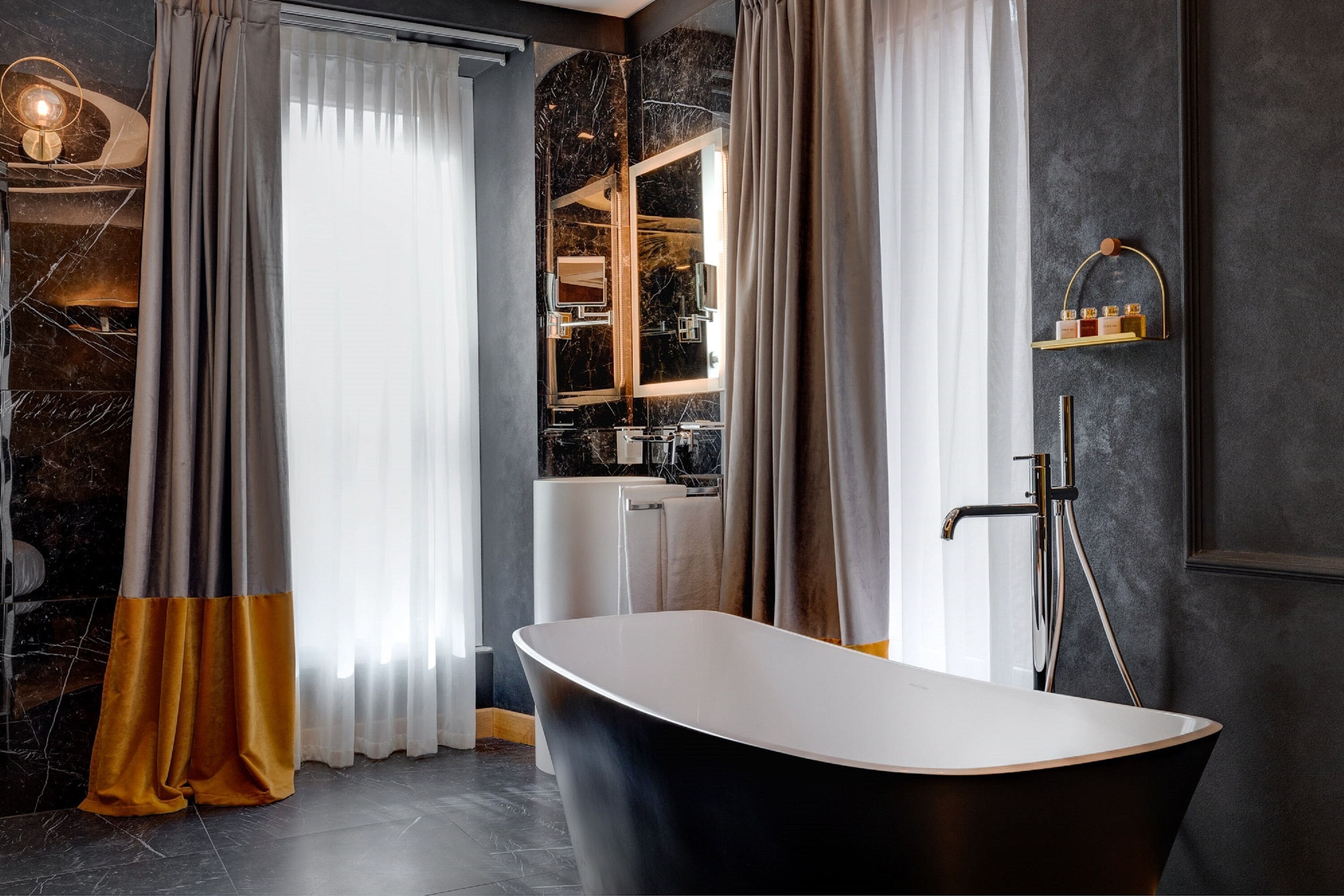 A modern bathroom with a freestanding bathtub, a large mirror, and a marble backsplash.