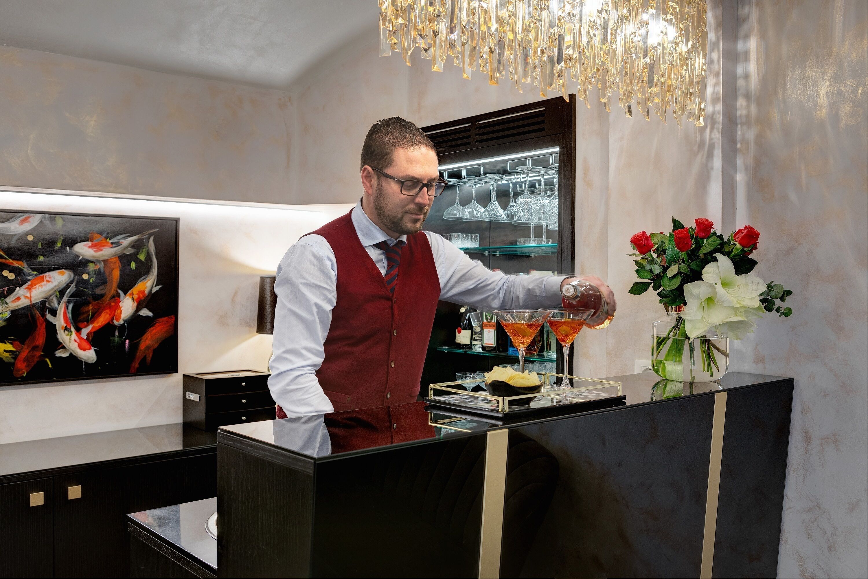 A bar area with a bartender, a martini glass, and a vase of flowers.