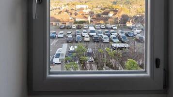 Ein Zimmer mit großem Fenster und Blick auf einen Parkplatz sowie Gebäude.