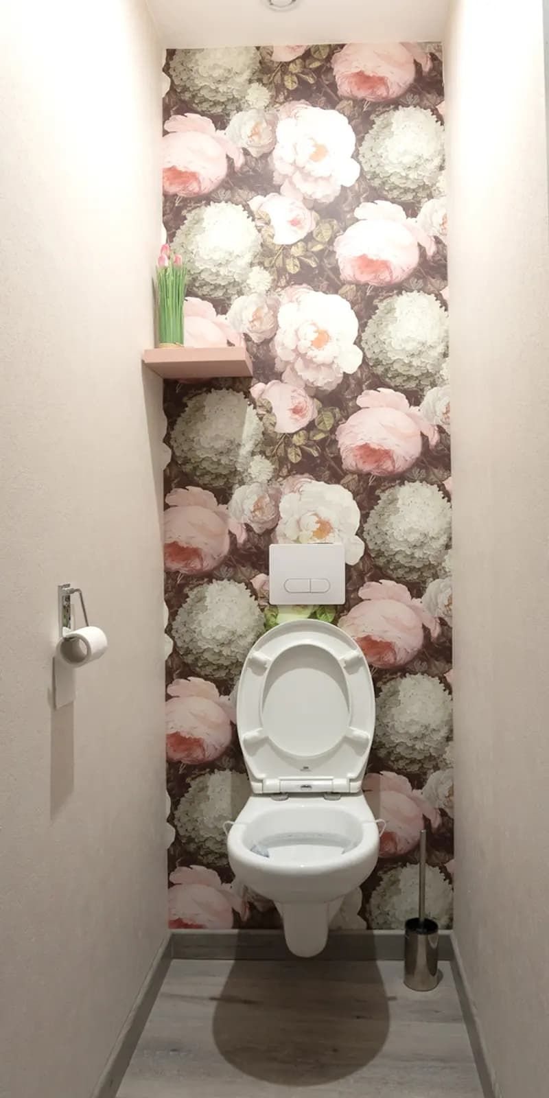 Une salle de bain équipée de toilettes, d’un porte-rouleau de papier toilette et d’une brosse pour les toilettes.