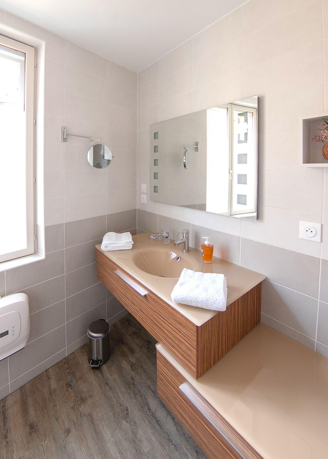 Un baño moderno con tocador doble, un espejo grande y una ventana.