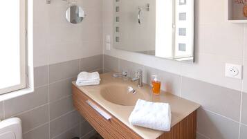 Un baño moderno con tocador doble, un espejo grande y una ventana.