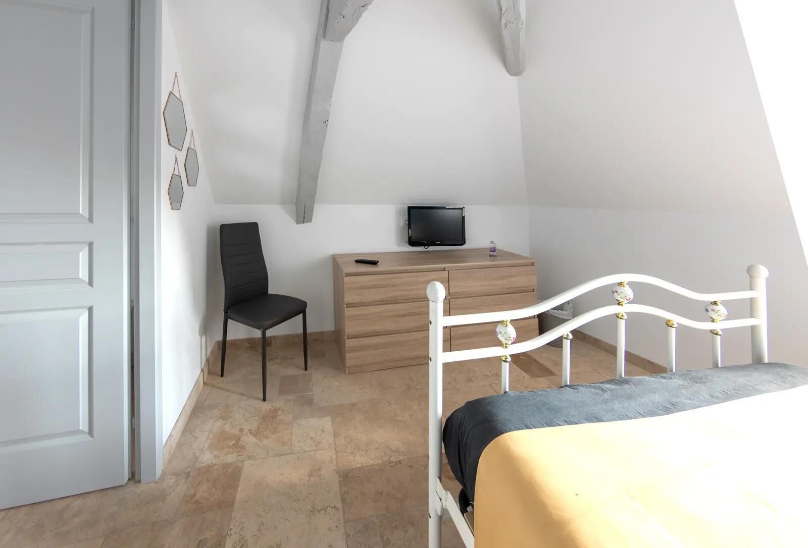 A bedroom with a bed, a desk, a chair, and a television.