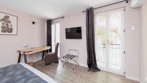 A bedroom with a bed, a desk, a chair, a TV, and a balcony with curtains. - Le Relais de la Poste (Gourdon)