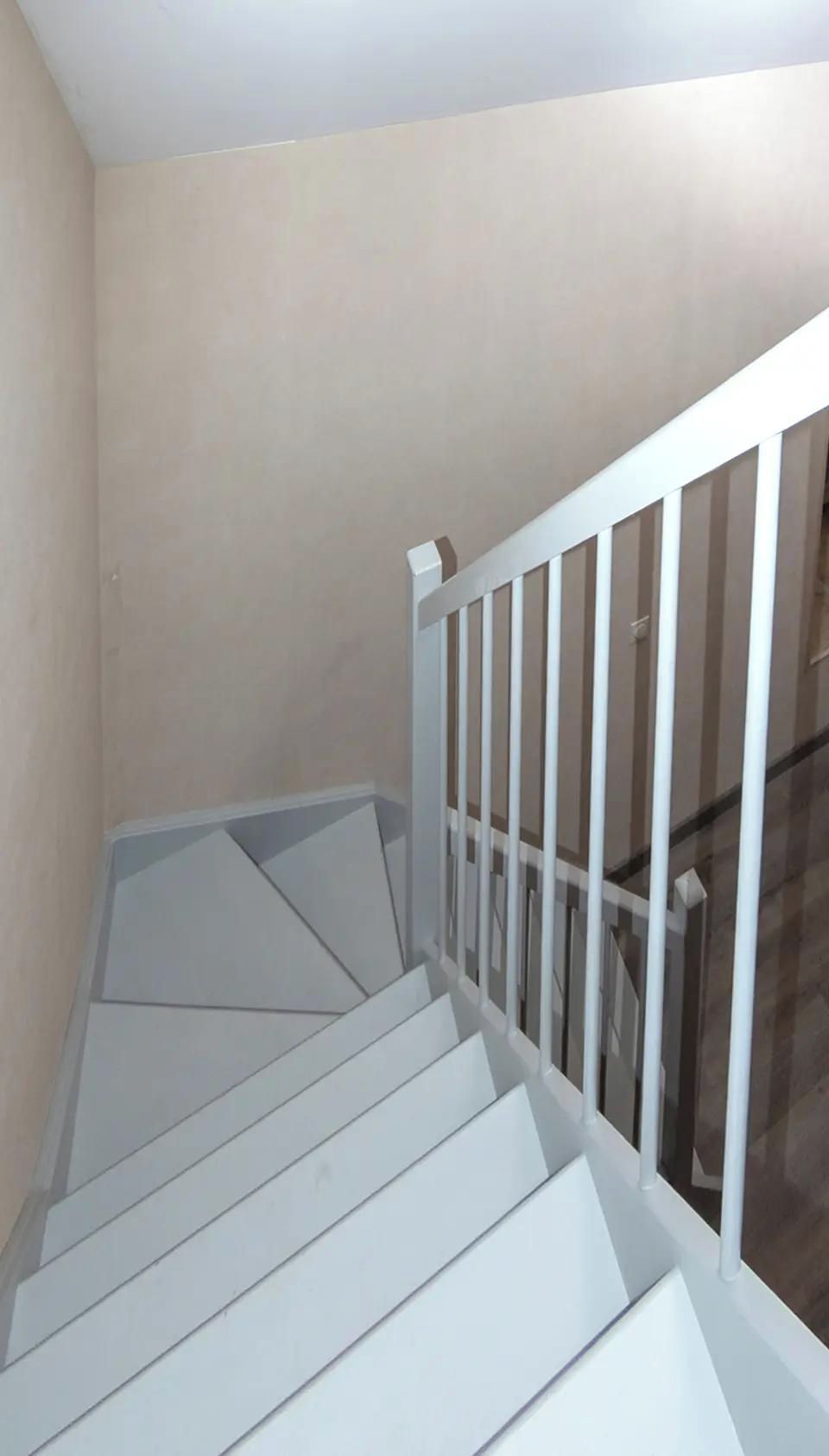 Una escalera con barandillas blancas y una pared color crema.