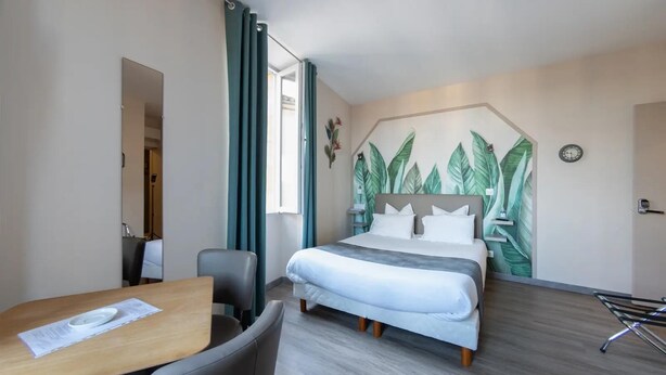 A hotel room with a bed, a desk, a chair, and a wall with a leaf pattern. - Le Relais de la Poste (Gourdon)