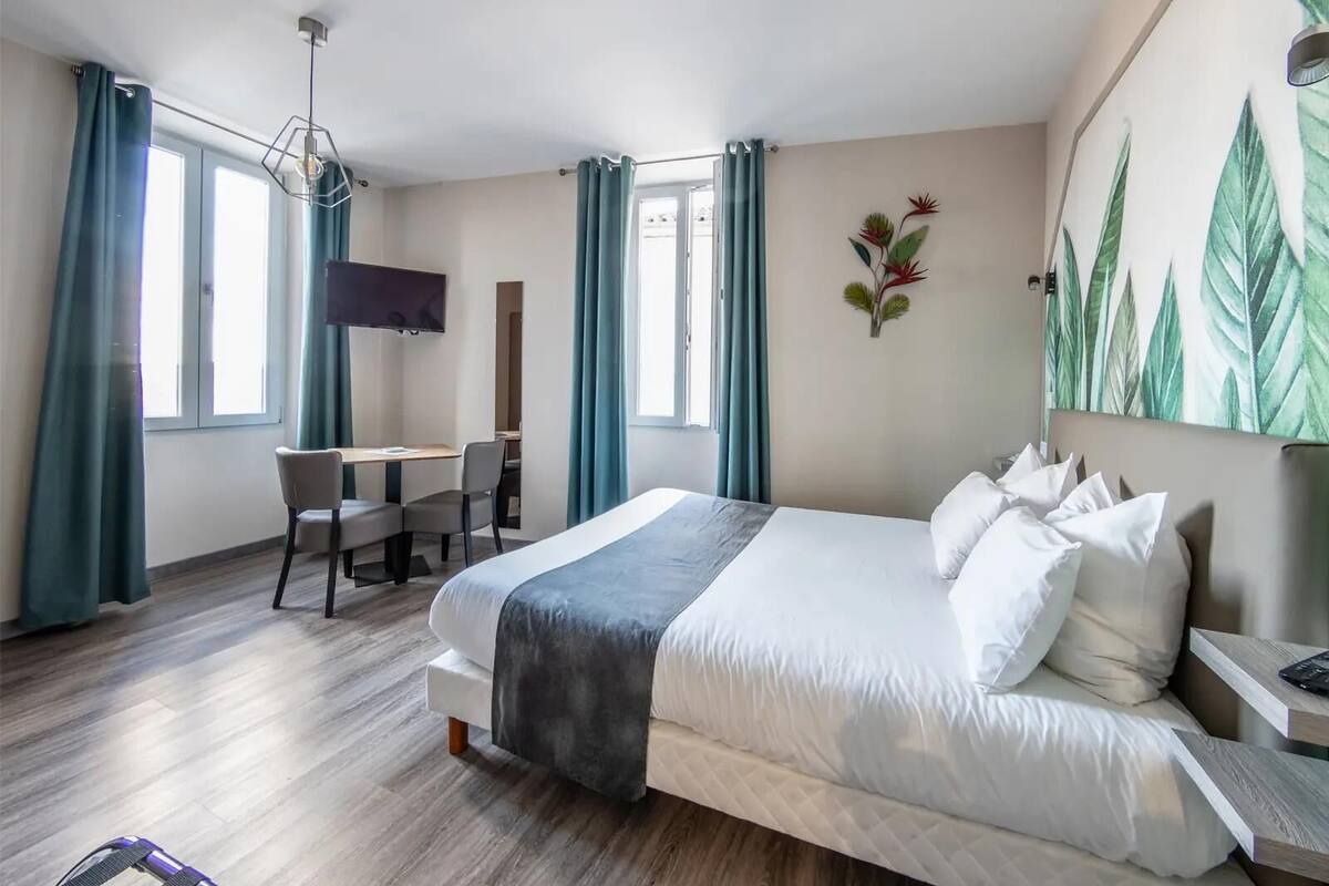 A hotel room with a large bed, a desk, a chair, and a TV.