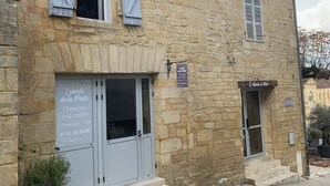 A stone building with two windows, a door, and a small sign. - Le Relais de la Poste (Gourdon)