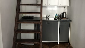 A kitchen with a wooden ladder, a sink, a kettle, and cabinets.