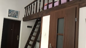 A room with a wooden staircase, a door with a frosted glass panel, and a wall-mounted air conditioning unit.
