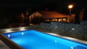Piscina rectangular con borde de azulejos, rodeada de un muro de piedra y escalones que bajan al agua.