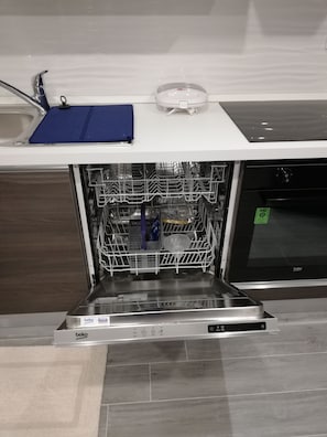 An open dishwasher with a blue mat on top, a dish rack inside, and a control panel with various settings. - Apartments Ivezic (Omisalj)