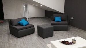 Una sala moderna con sofás grises, una mesa de centro blanca y piso gris.