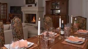 A dining room with a fireplace, wooden furniture, and a table set for a meal.