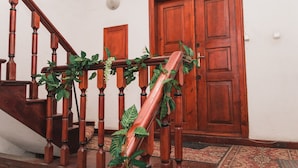 A wooden staircase with a handrail, a door, and a wall-mounted light fixture. - Filin Apartment (Kraków)