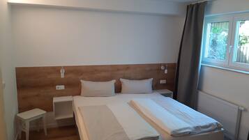 Una cama bien hecha con cabecera de madera, dos mesitas de noche y una ventana con cortinas.
