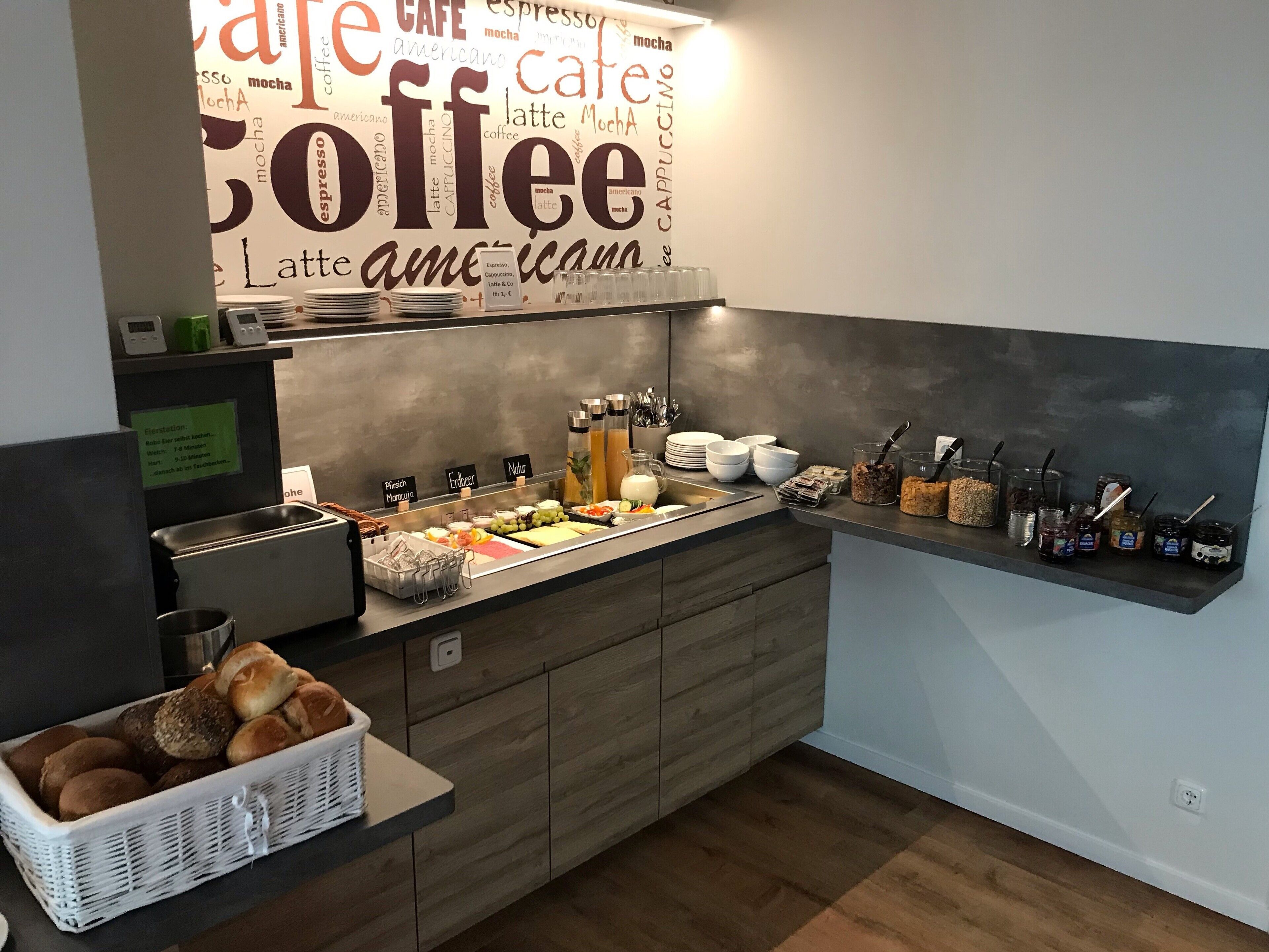 A breakfast buffet area with a coffee-themed wall, a variety of food options, and a coffee machine.