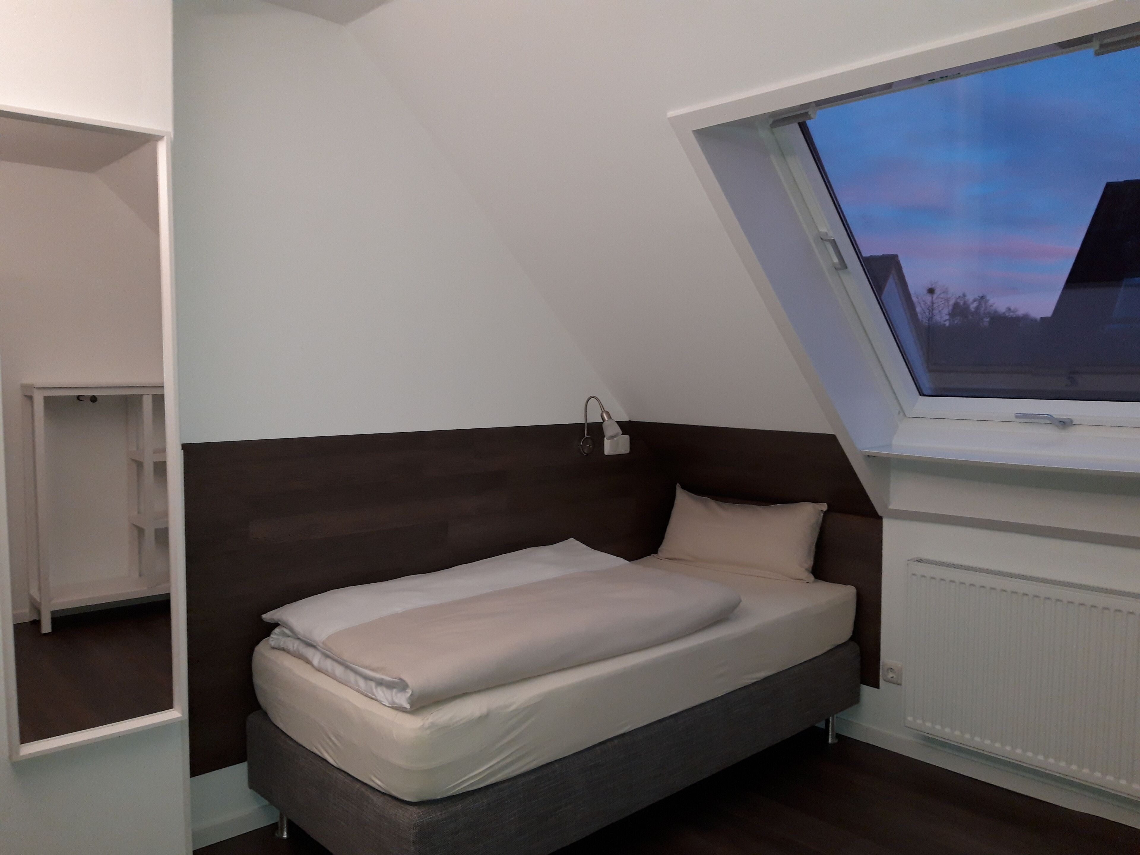 Ein Schlafzimmer mit Bett, Fenster und Heizkörper.