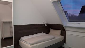 A bedroom with a bed, a window, and a radiator.
