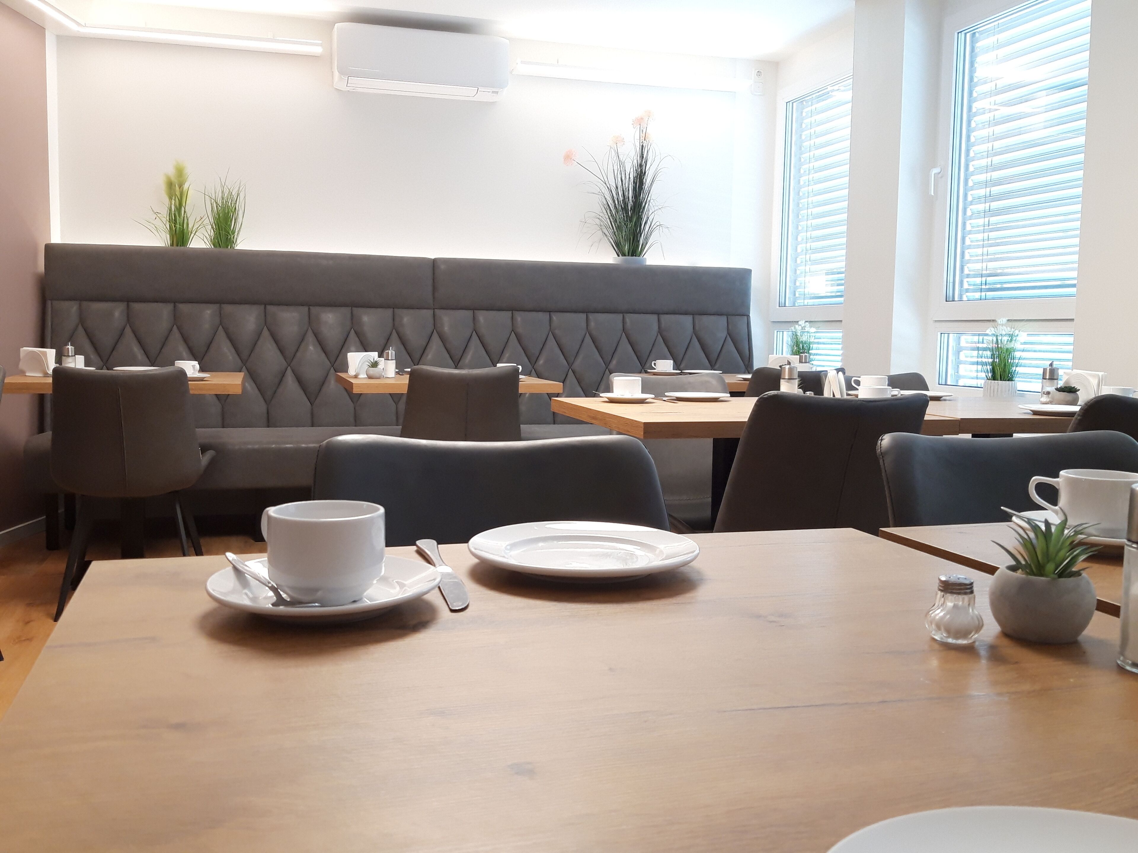 A modern dining area with a cushioned booth seating and wooden tables.