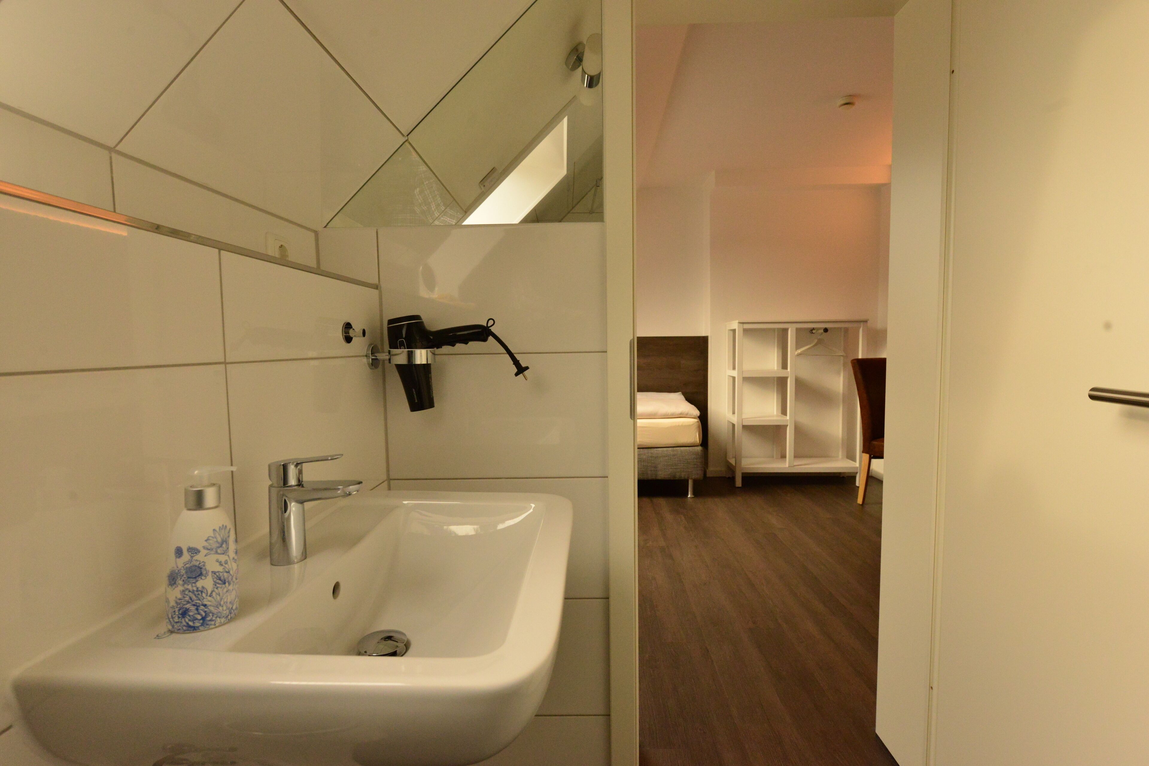 A modern bathroom with a white sink, a mirror, and a showerhead.
