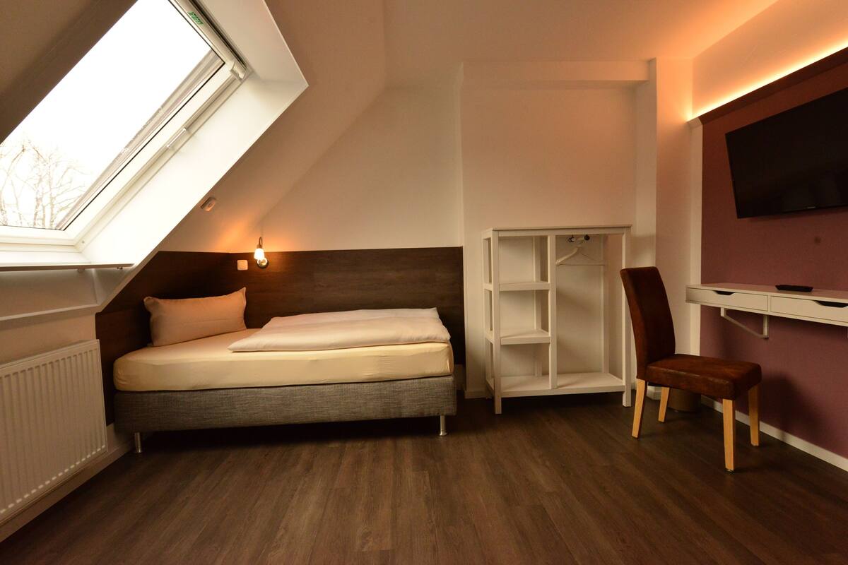 A bedroom with a bed, a desk, a chair, and a wardrobe.