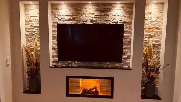 Een moderne woonkamer met een stenen accentmuur, een flatscreen televisie en een haard.