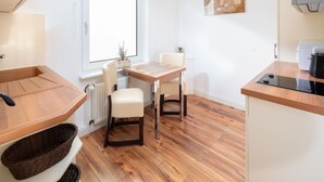 Une cuisine de taille réduite comprenant une table à manger, deux chaises, un radiateur et une fenêtre.