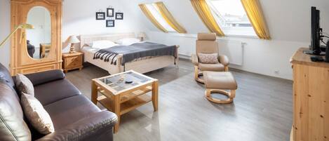 Et moderne soveværelse med seng, sofa, stol, skrivebord og garderobeskab.