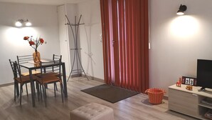 A modern living room with a dining table, chairs, a sofa, a TV, and a red curtain.
