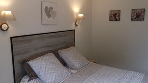 A bedroom with a wooden headboard, two bedside lamps, and a bed with patterned bedding.