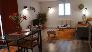 A modern living room with a dining area, a sofa, a coffee table, and a TV.