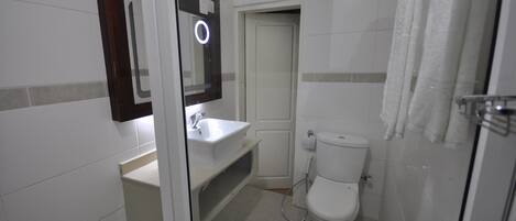 Un baño con lavamanos blanco, inodoro y zona de ducha.