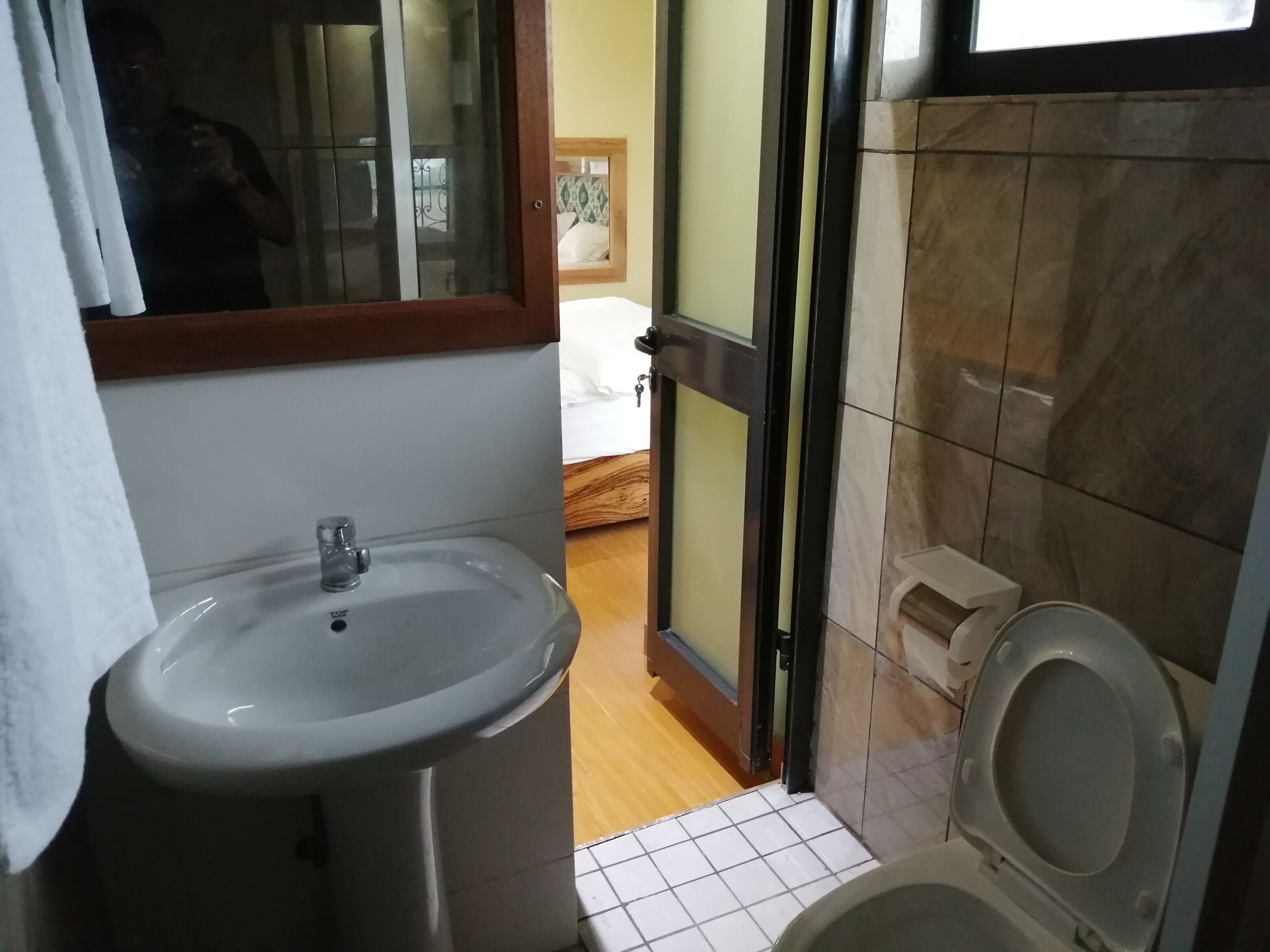 A bathroom with a sink, toilet, and a mirror with a wooden frame.