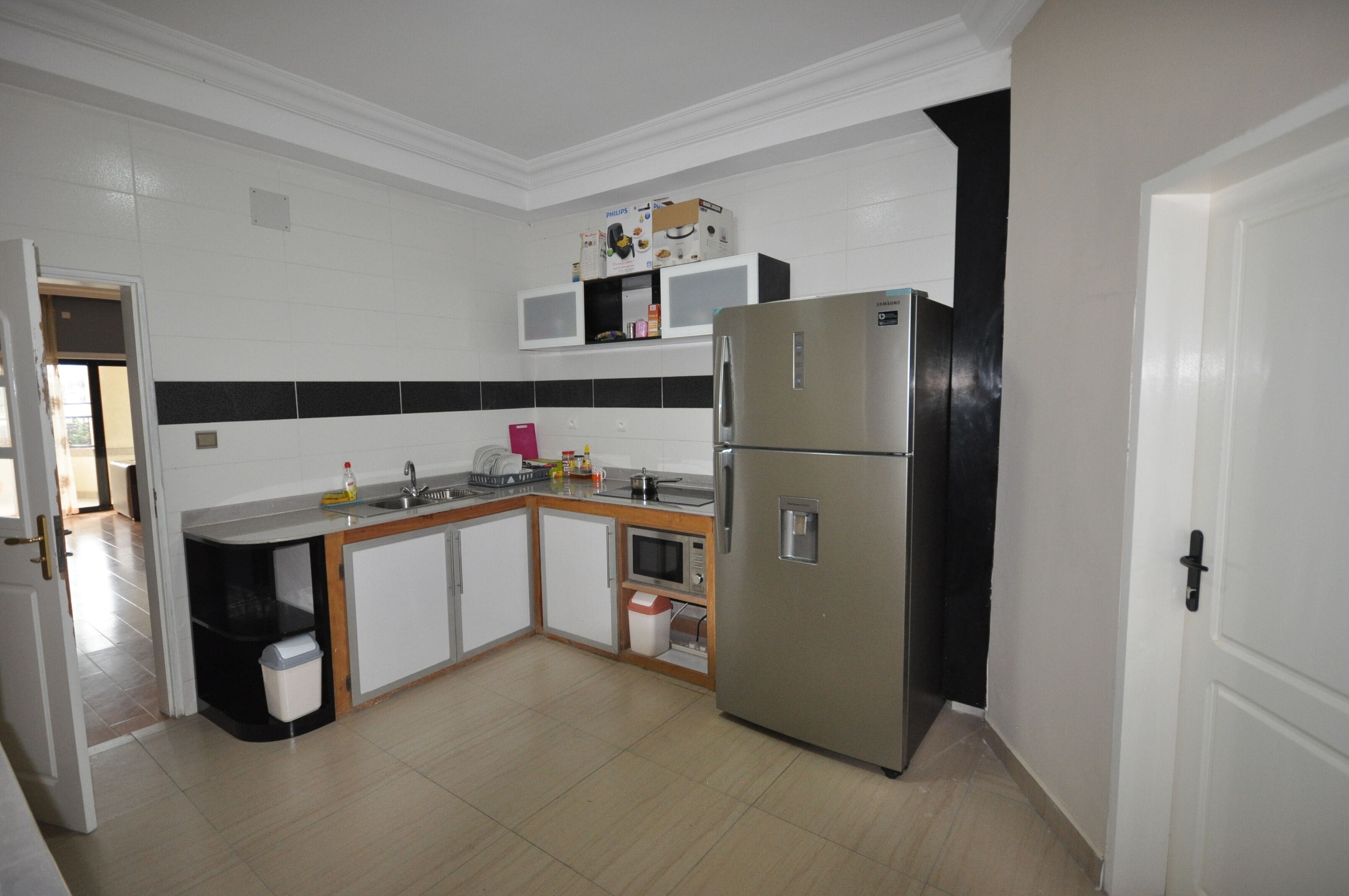 Una cocina moderna con armarios blancos, un refrigerador de acero inoxidable y un microondas.