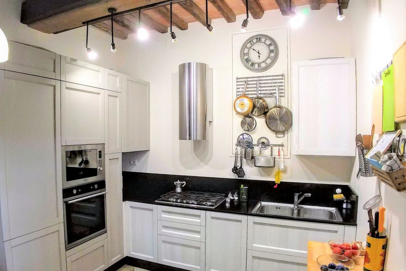 A modern kitchen with white cabinets, a stainless steel range, and a black countertop.