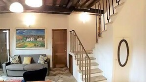 A living room with a sofa, a painting, a staircase, and a door. - THE AERIE - THE EAGLE'S NEST - large apartment in strategic location (Siena)