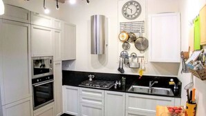 A modern kitchen with white cabinets, a stainless steel range, and a black countertop. - THE AERIE - THE EAGLE'S NEST - large apartment in strategic location (Siena)
