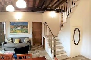 Un salon avec un canapé, un tableau, un escalier et une porte.