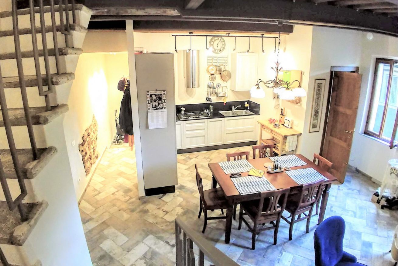 Une cuisine avec une table à manger, des chaises et un escalier.