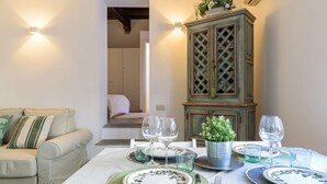 A dining area with a table set for two, a green cushioned bench, and a cabinet with a lattice design. - Moma 1 (Como)