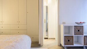 A bedroom with a bed, a wardrobe, and a console table with storage boxes. - Moma 1 (Como)