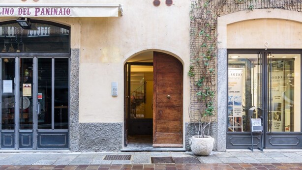 A building facade with a wooden door, a sign reading "LINO DEL PANINATO," and a potted plant. - Moma 1 (Como)