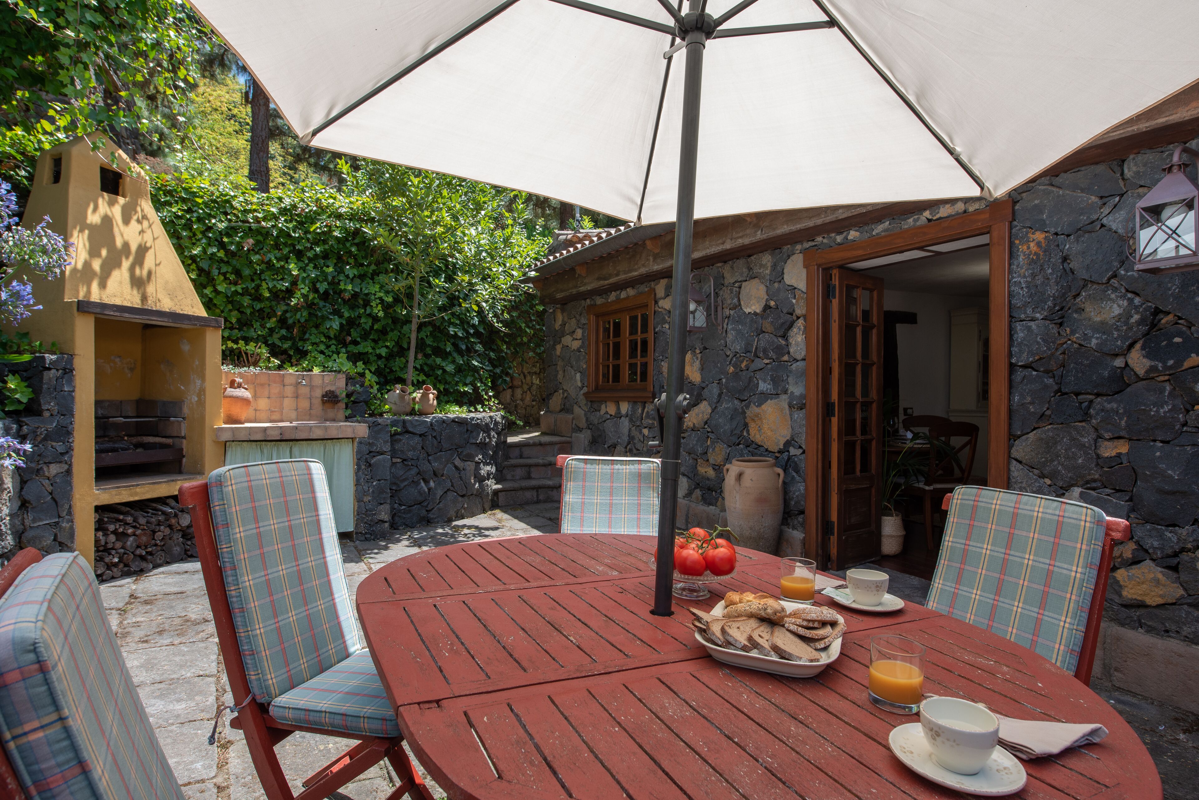 Une terrasse extérieure avec une table ronde, des chaises et un grand parasol.