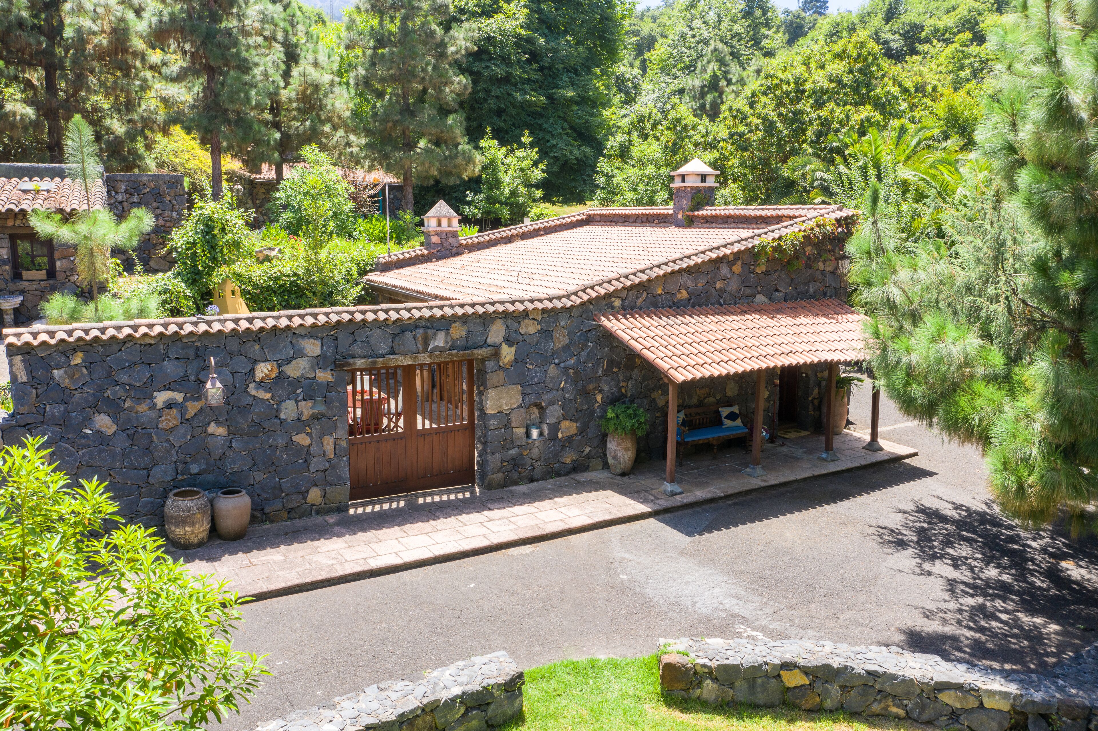 A stone building with a tiled roof, a wooden door, and a covered porch.