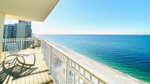 A balcony with a view of the ocean and a building in the background. - Crystal Shores Condominiums by ALBVR (Gulf Shores)