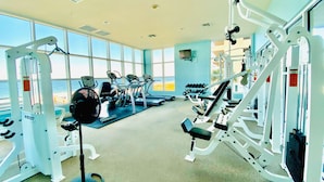 A gym with cardio machines, weightlifting equipment, and dumbbells. - Crystal Shores Condominiums by ALBVR (Gulf Shores)