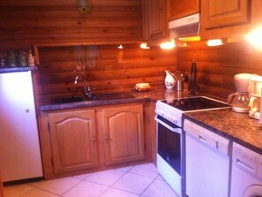 Eine kompakte Küche mit Holzausstattung, Backofen, Geschirrspüler und einer Kaffeemaschine.